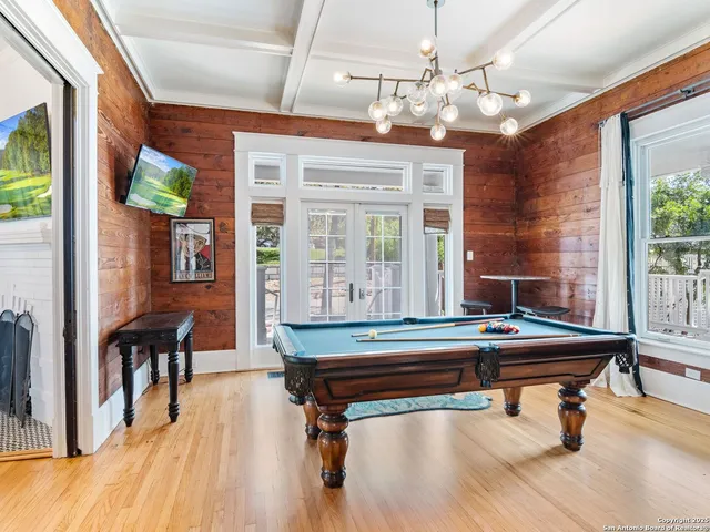 a room with pool table and wooden floor