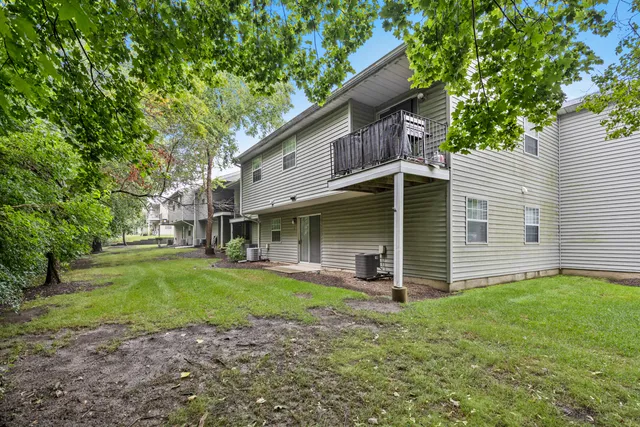 a view of a white house with a yard and large tree