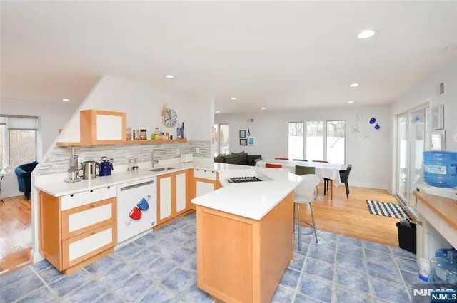 a kitchen with stainless steel appliances kitchen island granite countertop a sink a stove top oven a dining table and chairs