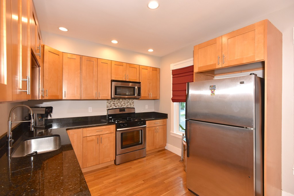 7 Chadwick Street Worcester, MA 01605 - Photo 15 of 30 a kitchen with stainless steel appliances granite countertop a refrigerator a sink a stove and white cabinets with wooden floor