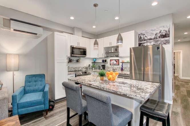 1409 Victorian Alley Sacramento, CA 95818 - Photo 9 of 45 a kitchen with stainless steel appliances granite countertop a stove a refrigerator a kitchen island a dining table and chairs