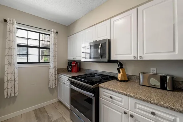 a kitchen with granite countertop white cabinets stainless steel appliances and sink