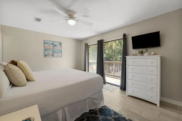 a bedroom with a bed television on desk and a window