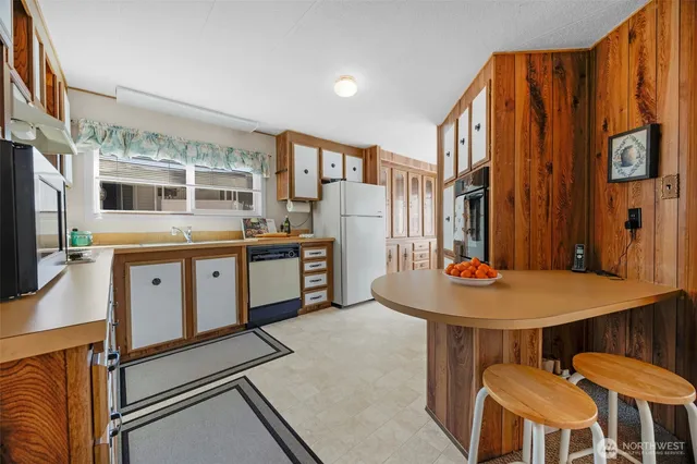 a kitchen with stainless steel appliances kitchen island granite countertop a table chairs and a refrigerator