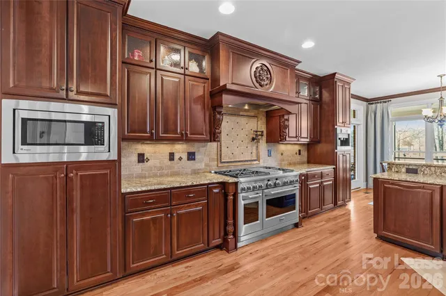 a kitchen with stainless steel appliances granite countertop a stove cabinets and wooden floor