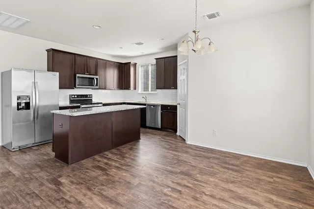 a view of kitchen with refrigerator stove and wooden floor