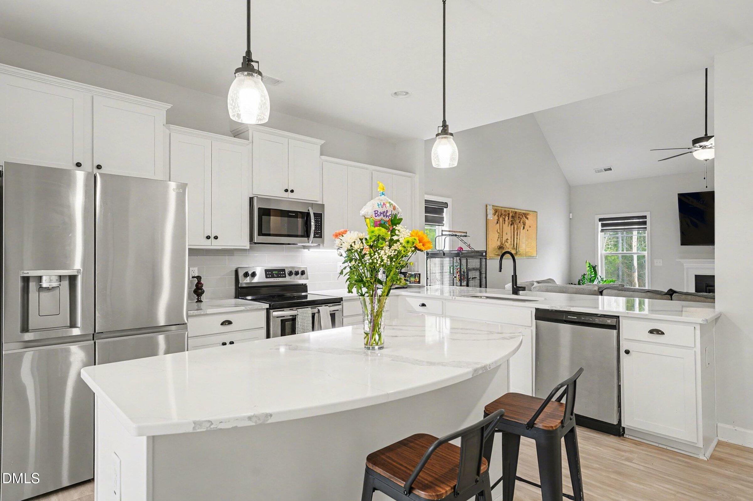 365 Timber Skip Drive Spring Lake, NC 28390 - Photo 13 of 33 a kitchen with stainless steel appliances a stove a sink a microwave a refrigerator a dining table and chairs with wooden floor