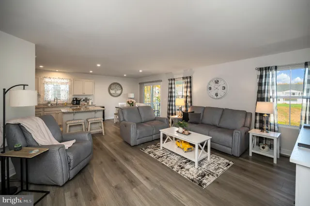 a kitchen with stainless steel appliances granite countertop a refrigerator a sink dishwasher a stove and a dining table with wooden floor