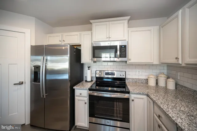 a kitchen with stainless steel appliances granite countertop white cabinets a stove a sink and dishwasher