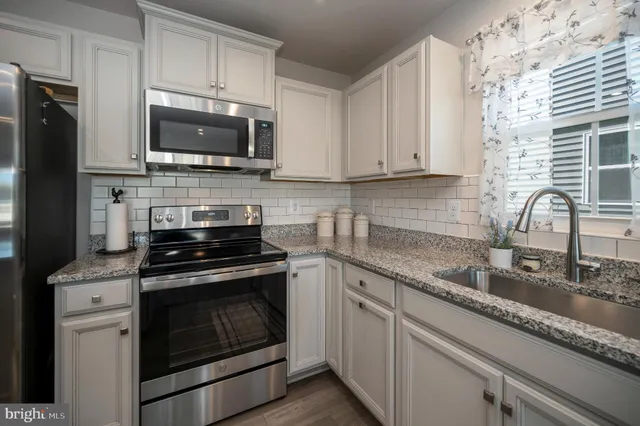 a kitchen with stainless steel appliances granite countertop a sink a stove a cabinets and a window