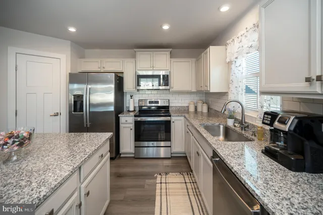 a kitchen with stainless steel appliances granite countertop a table chairs sink refrigerator and cabinets