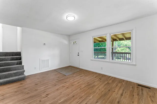 a view of an empty room with wooden floor and a window