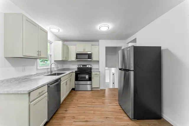 a kitchen with a refrigerator a stove top oven a sink and dishwasher with wooden floor