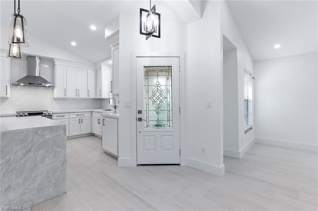 116 Fountain Circle Naples, FL 34119 - Photo 5 of 24 a kitchen with white cabinets and white appliances