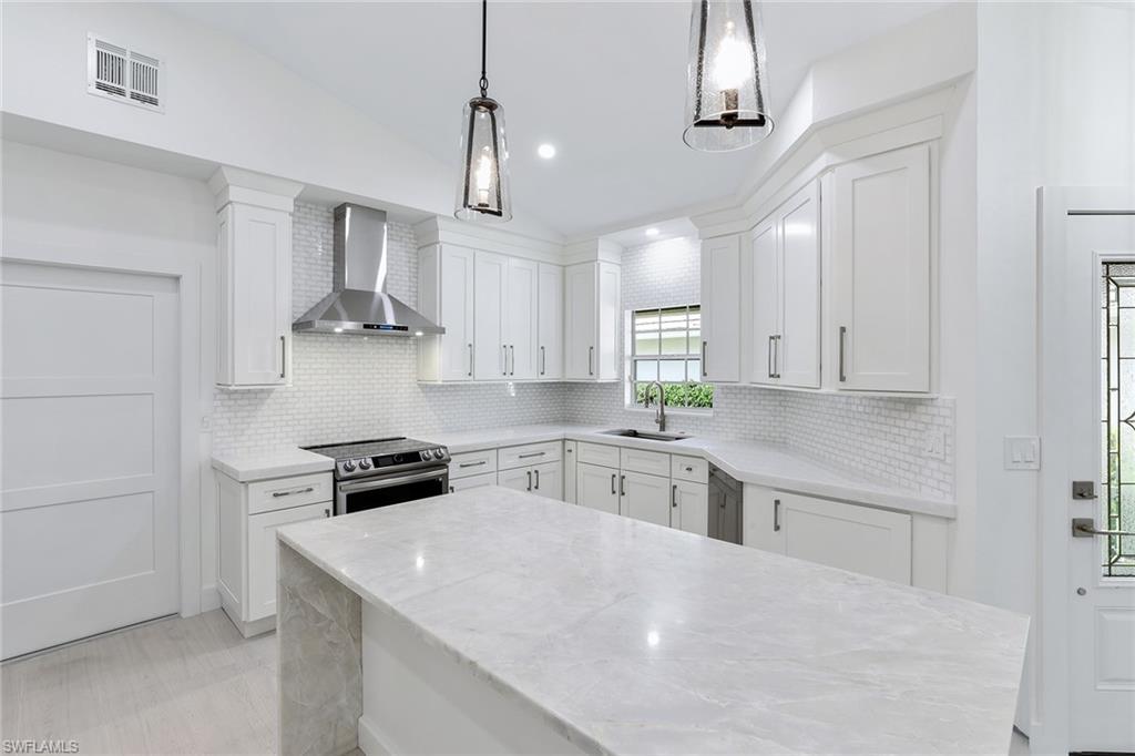 116 Fountain Circle Naples, FL 34119 - Photo 9 of 24 a kitchen with stainless steel appliances granite countertop a sink a stove a refrigerator and white cabinets