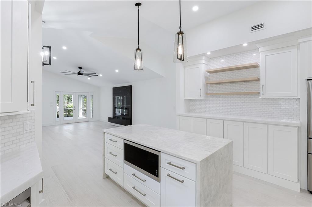 116 Fountain Circle Naples, FL 34119 - Photo 10 of 24 a view of a kitchen with a stove a microwave and wooden floor