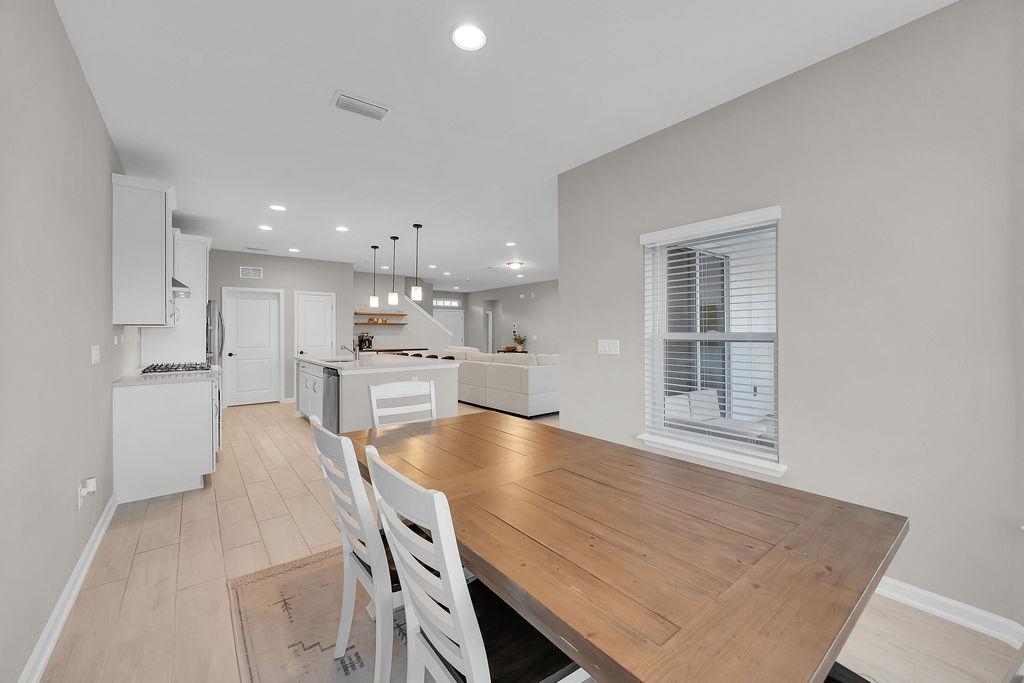 161 Goldcrest Way St. Augustine, FL 32092 - Photo 12 of 52 a large kitchen with kitchen island a stove a sink a refrigerator and white cabinets with wooden floor