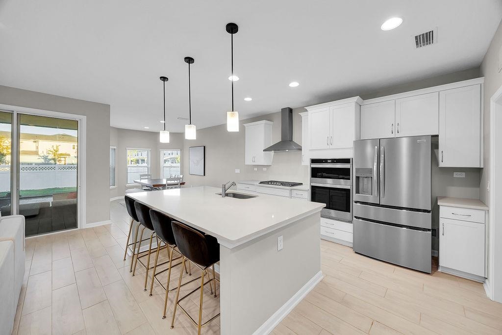 161 Goldcrest Way St. Augustine, FL 32092 - Photo 7 of 52 a kitchen with stainless steel appliances kitchen island a table chairs refrigerator and sink