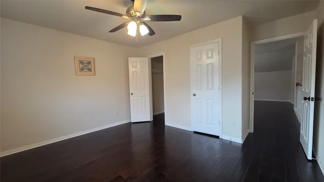 an empty room with wooden floor closet and windows