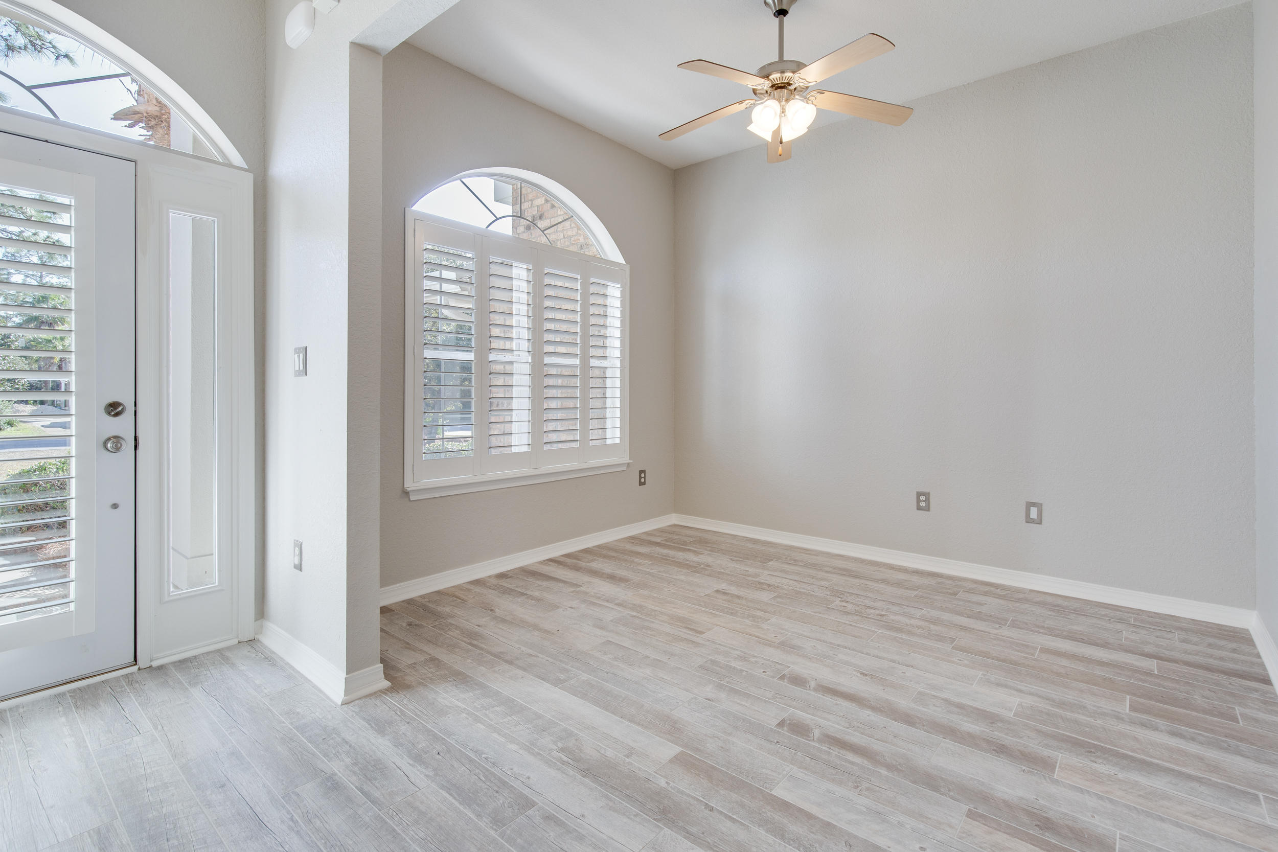 121 East Shipwreck Road Santa Rosa Beach, FL 32459 - Photo 4 of 45 an empty room with wooden floor chandelier fan and windows