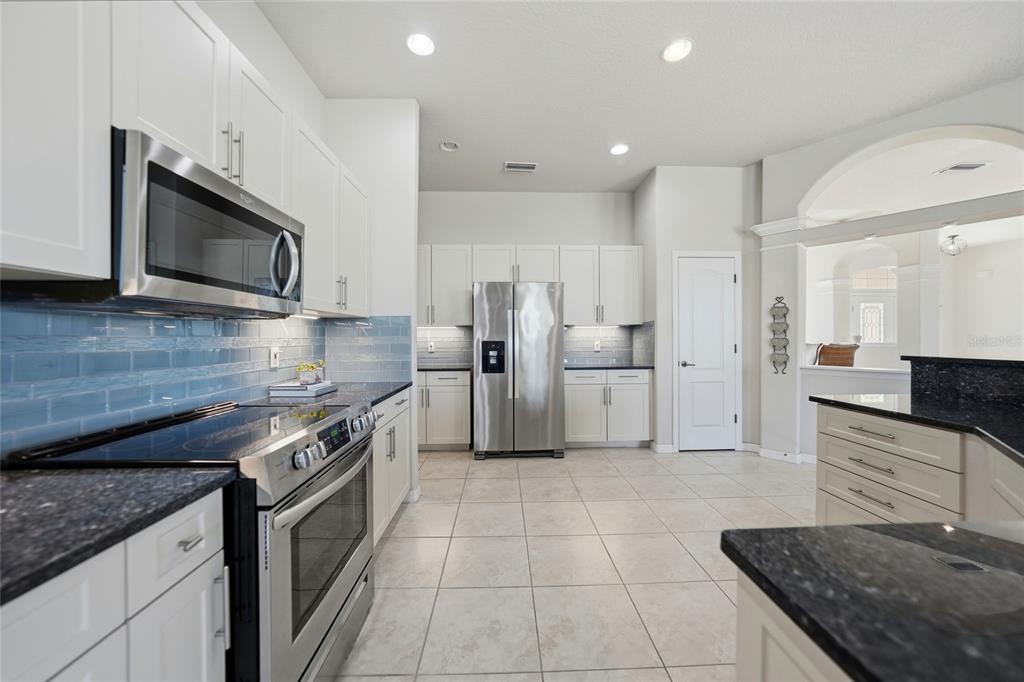 5455 Graves Terrace Port Charlotte, FL 33981 - Photo 12 of 54 a large kitchen with stainless steel appliances granite countertop a stove a sink and a microwave