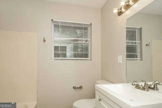 a bathroom with a sink a toilet and a window