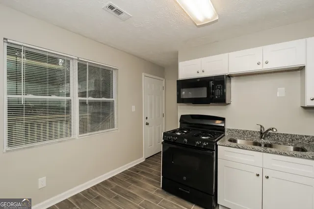a kitchen with granite countertop white cabinets and black appliances