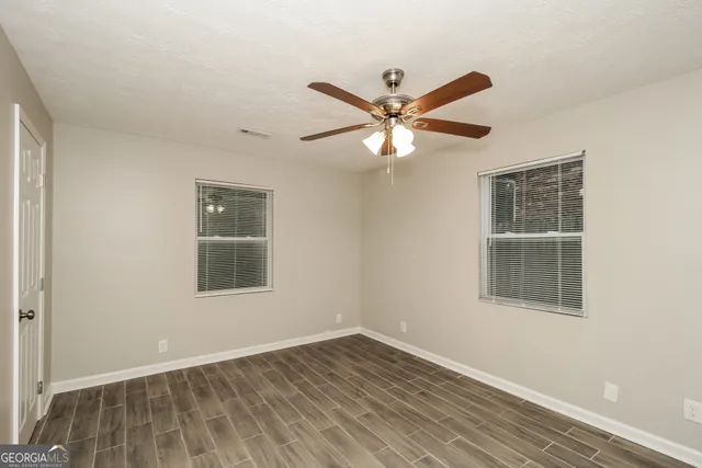 an empty room with wooden floor closet and windows