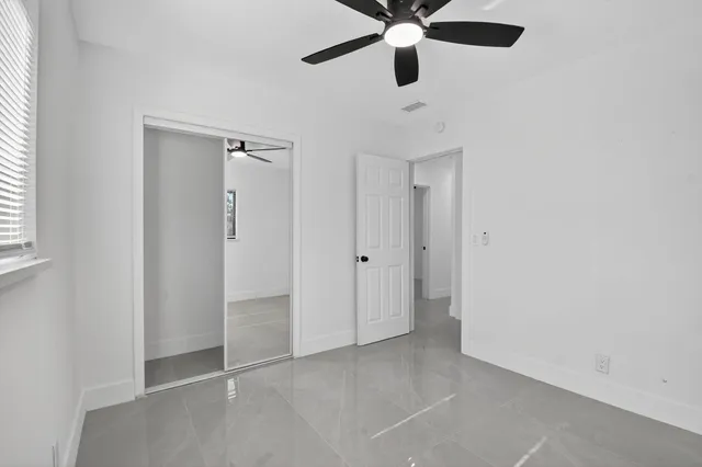an empty room with a ceiling fan and a window