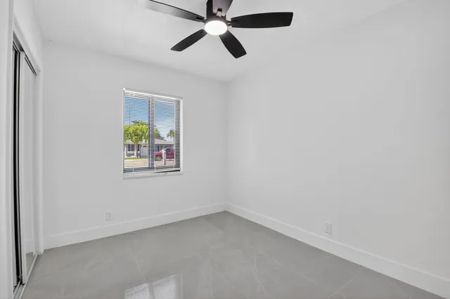 an empty room with window and ceiling fan