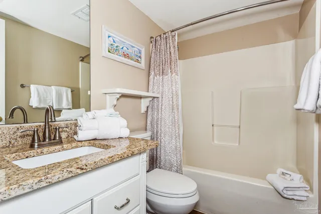 a bathroom with a granite countertop sink mirror vanity and toilet