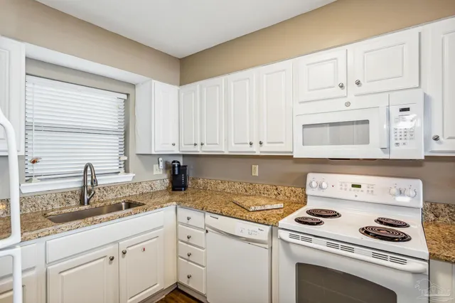 a kitchen with granite countertop white cabinets and white appliances