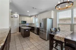 a kitchen with stainless steel appliances granite countertop a stove a refrigerator a sink a dining table and chairs