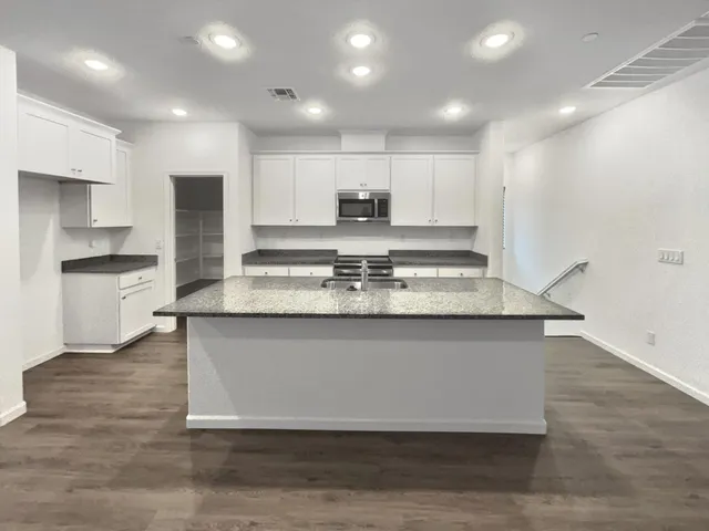 a kitchen with granite countertop white cabinets and stainless steel appliances