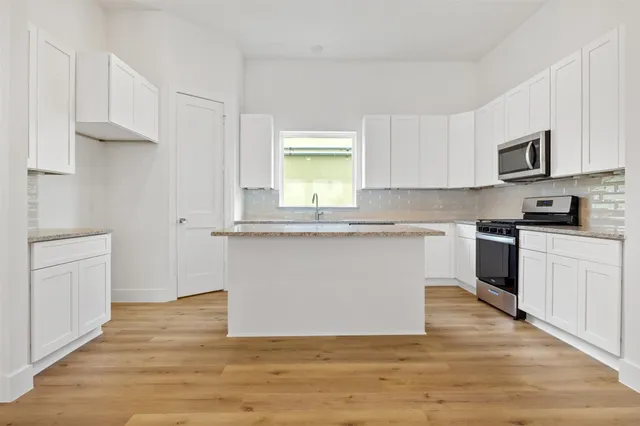 a kitchen with granite countertop a sink cabinets stainless steel appliances and a window