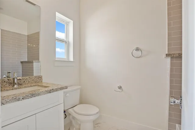 a bathroom with a granite countertop sink toilet and shower