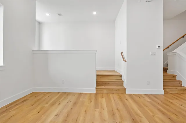 a view of an empty room with wooden floor and a bathroom