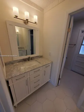 a bathroom with a granite countertop sink and a mirror
