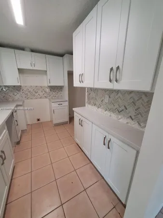 a kitchen with white cabinets a sink dishwasher and a stove with wooden floor