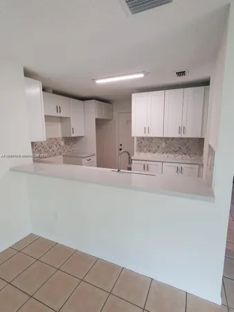 a kitchen with granite countertop white cabinets and stainless steel appliances