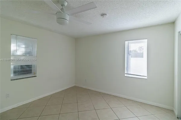 an empty room with windows and fan