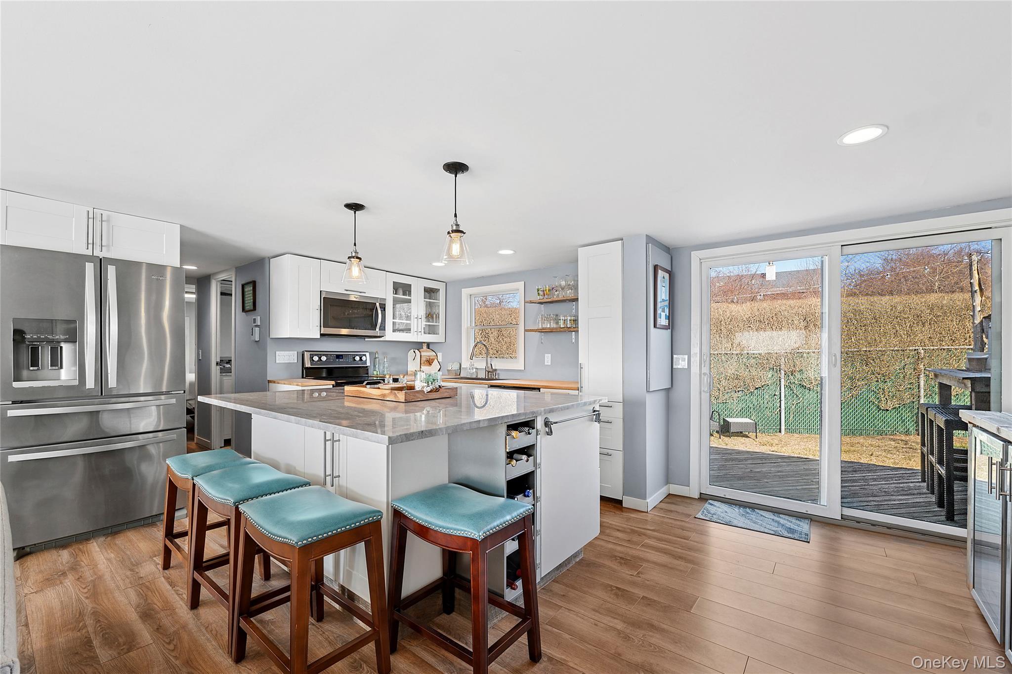 100 Deforest Road, Unit 433 Montauk, NY 11954 - Photo 3 of 26 a kitchen with stainless steel appliances kitchen island granite countertop a table chairs and a refrigerator