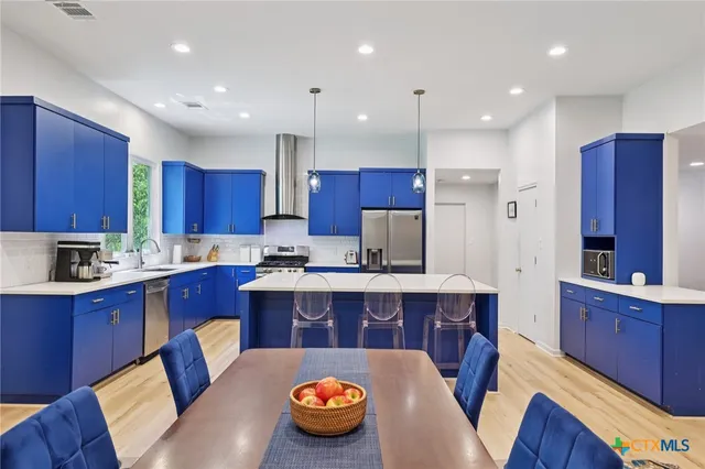 a large kitchen with cabinets chairs and wooden floors