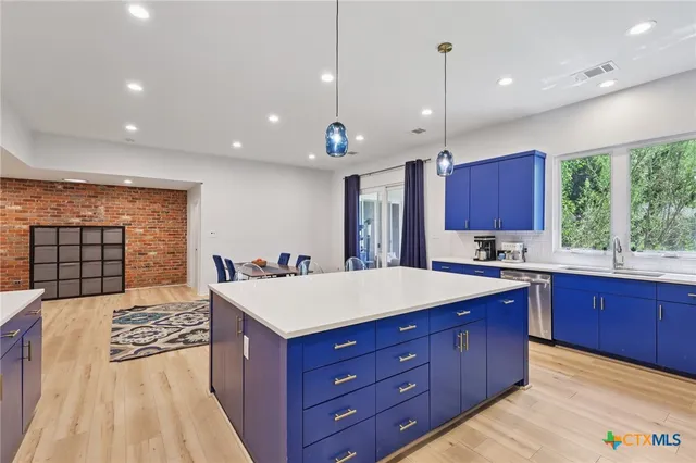 a large kitchen with kitchen island a stove a sink dishwasher and a wooden cabinets with large window