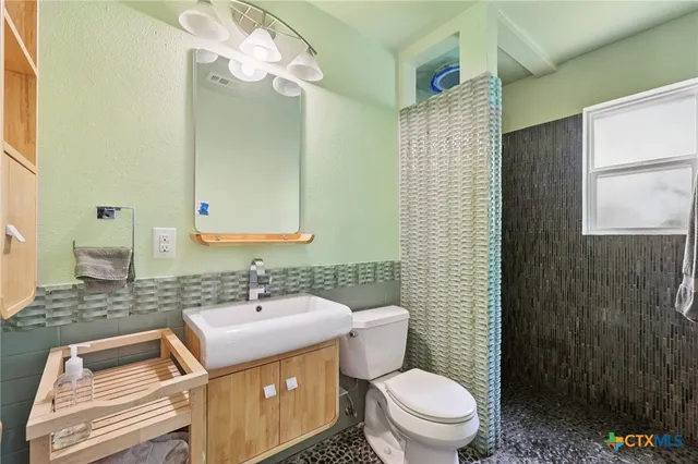 a bathroom with a sink a toilet and shower