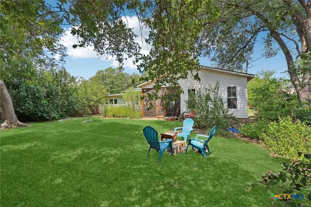 a view of a chair and table in backyard of the house