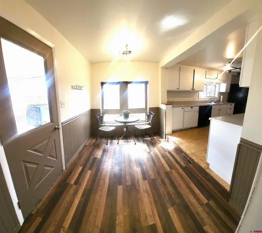 a living room with stainless steel appliances furniture wooden floor and a kitchen view
