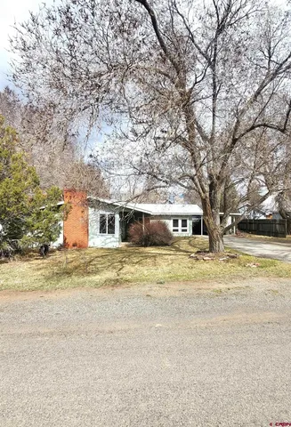 a view of a house with a yard and large trees