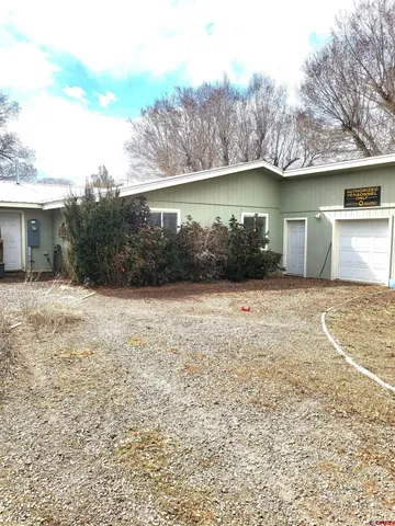 a front view of house with yard and trees in the background