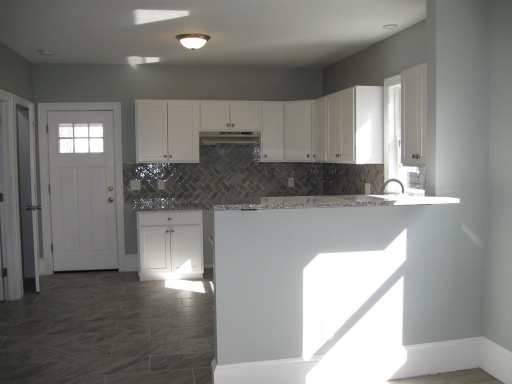 12 Alderman Street Springfield, MA 01108 - Photo 10 of 27 a kitchen with stainless steel appliances granite countertop a refrigerator a sink a stove and white cabinets with wooden floor